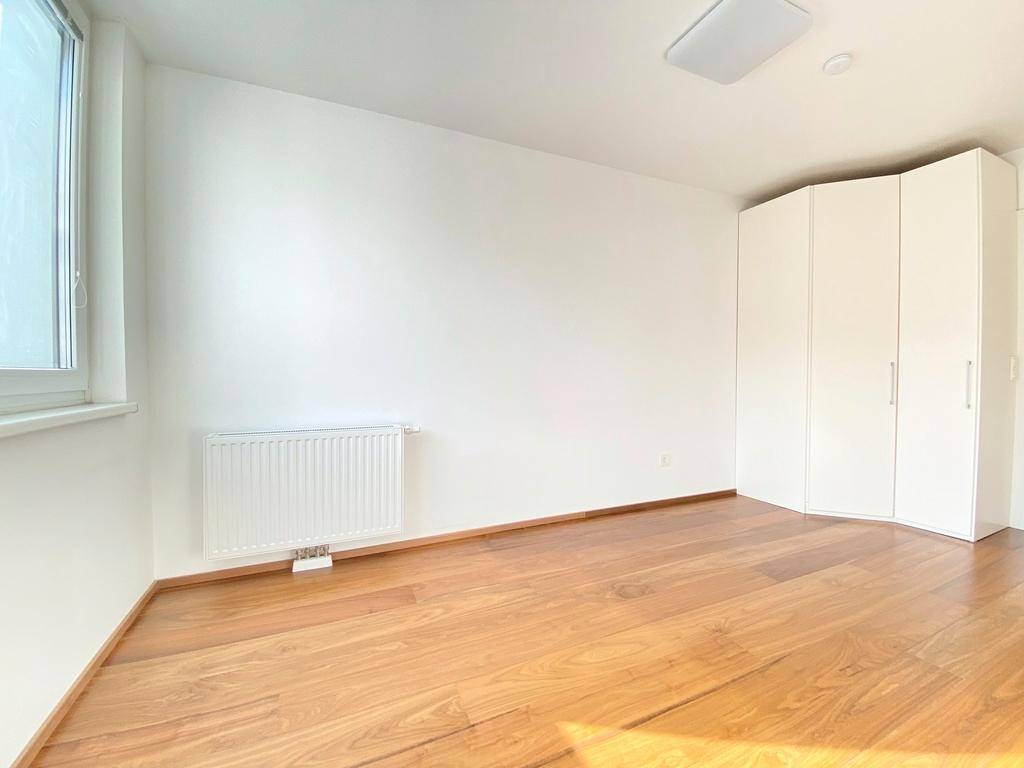 Geräumiges Schlafzimmer mit Holzboden, weißem Kleiderschrank und viel natürlichem Licht.