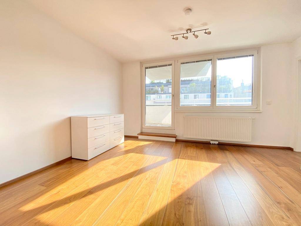 Heller Wohnraum mit großen Fenstern, Holzboden und Blick nach draußen.