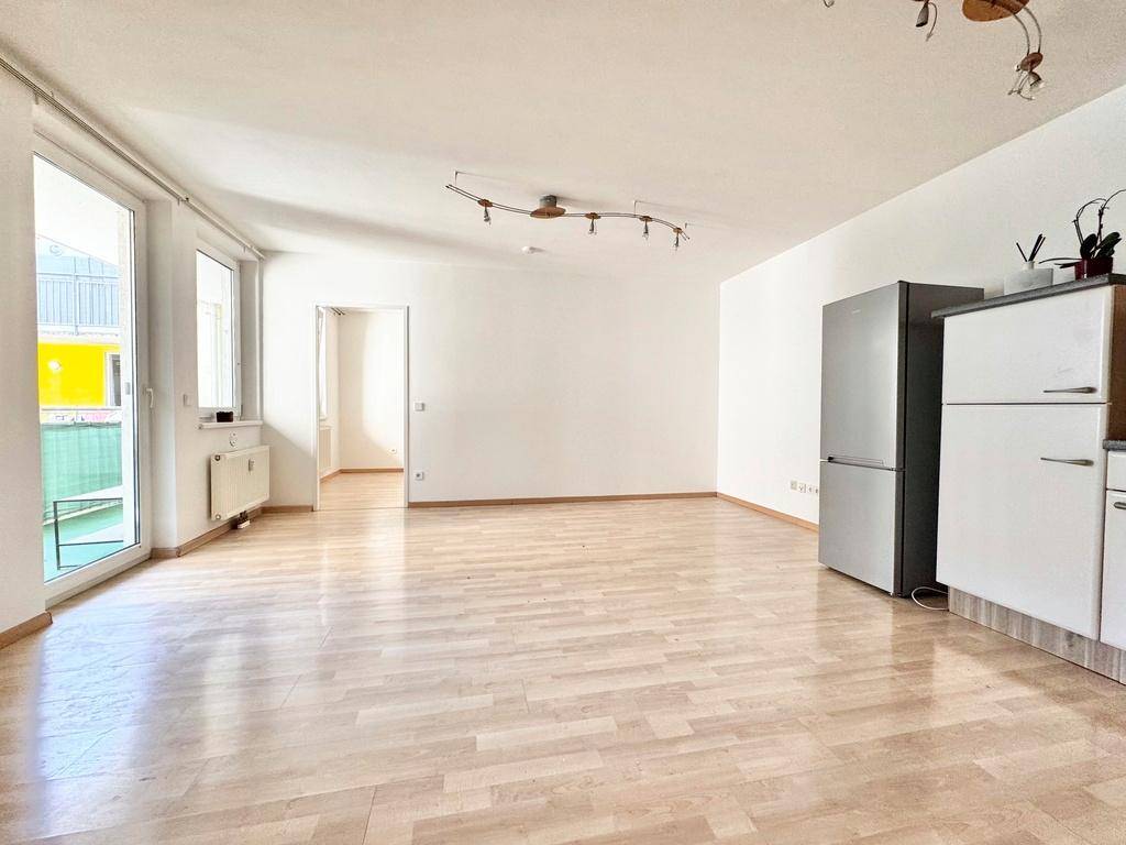 Offener Wohnbereich mit Laminatboden, viel Tageslicht und Platz für eine integrierte Küchenzeile.
