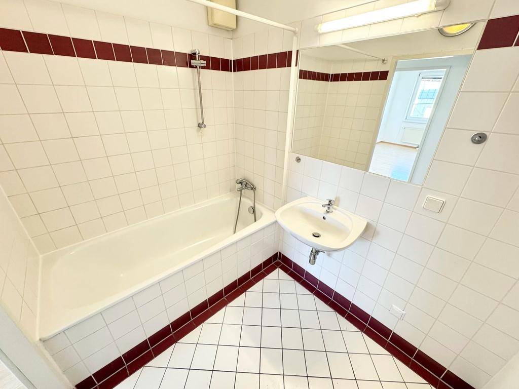 Badezimmer mit Badewanne, Waschbecken und weiß-roten Fliesen im klassischen Stil.