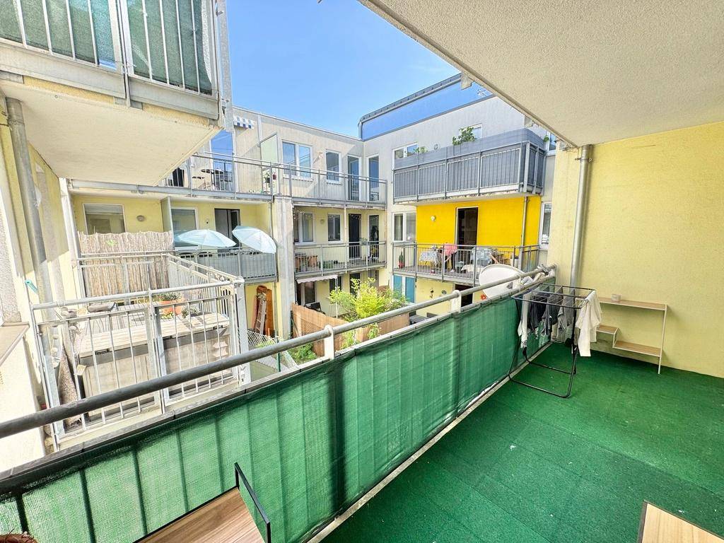 Geräumiger Balkon mit Blick auf den begrünten Innenhof und weitere Balkone der umliegenden Gebäude.