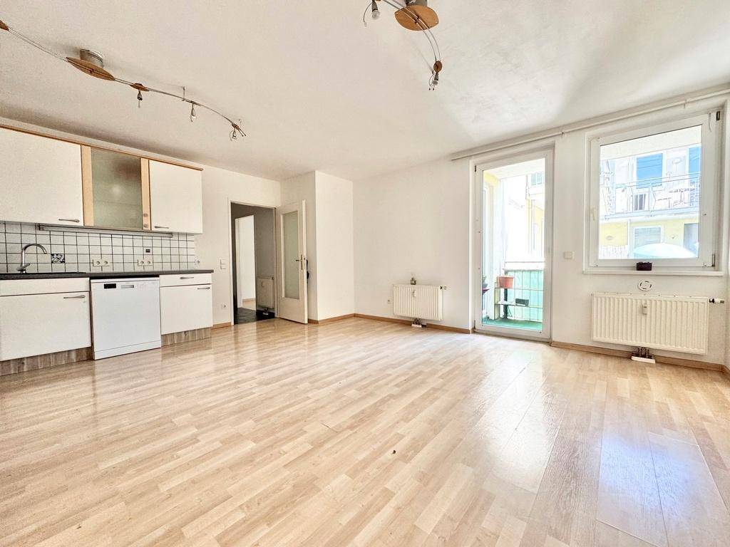 Heller Wohnbereich mit integrierter Küche, Laminatboden und direktem Zugang zum Außenbereich.