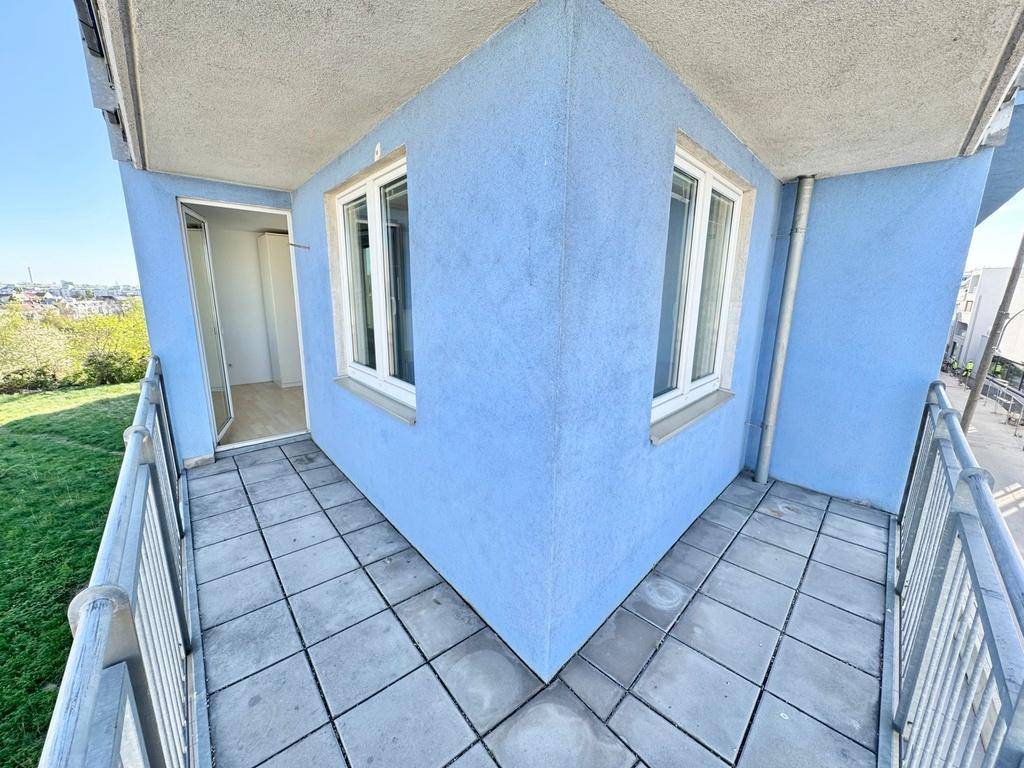 Eckbalkon mit blauer Fassade und Fliesenboden, bietet einen hellen Außenbereich.