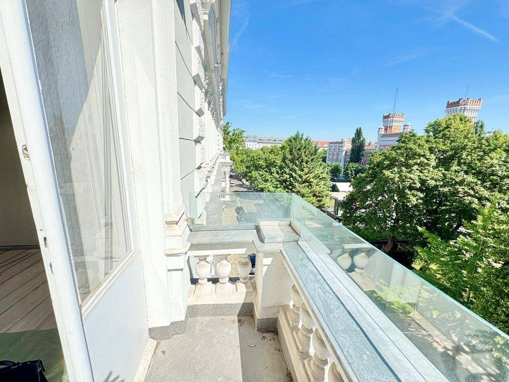 Balkon mit Zugang zum Innenbereich, Glasbrüstung und Blick auf die umliegende Stadtlandschaft.