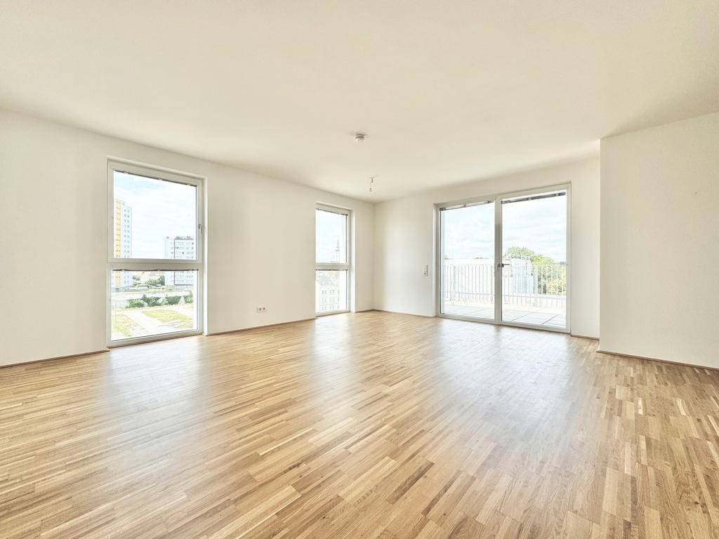 Großzügiger, heller Wohnraum mit Parkettboden und großen Fenstern zur Terrasse.