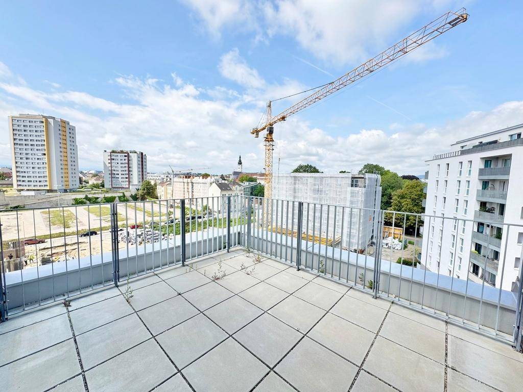 Weitläufige Terrasse mit Metallgeländer und Ausblick auf die Stadt und Baustellen.