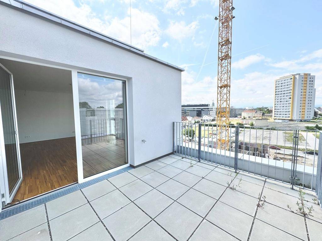 Helle Terrasse mit Zugang zu einem Innenraum und Blick auf die städtische Umgebung.