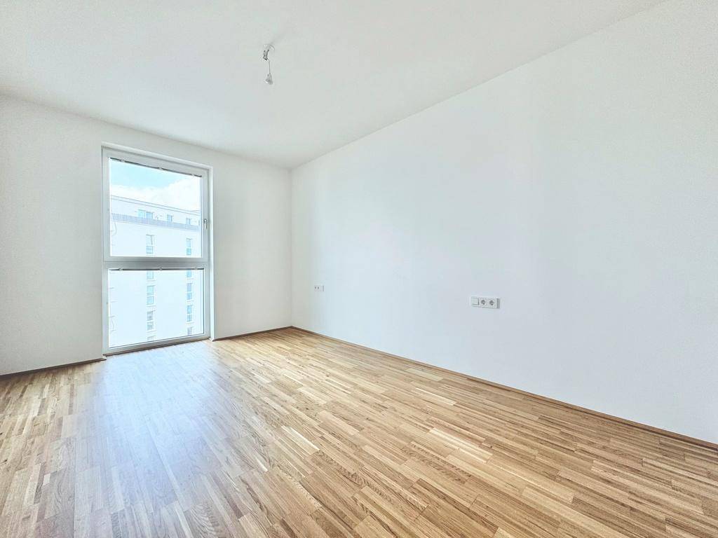 Lichtdurchflutetes Zimmer mit Parkett und weitem Blick aus dem großen Fenster.