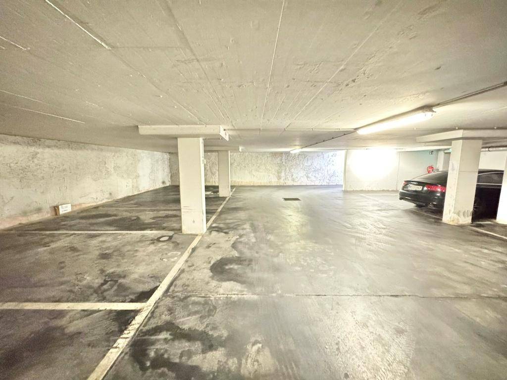 Helle Tiefgarage mit mehreren freien Stellplätzen und einem geparkten Fahrzeug.