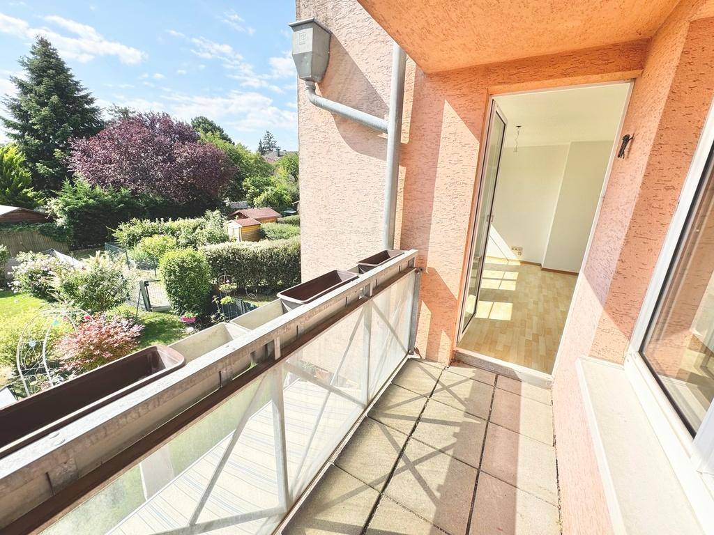 Heller Balkon mit Glasgeländer und weitem Blick ins Grüne, ideal zum Entspannen im Freien.
