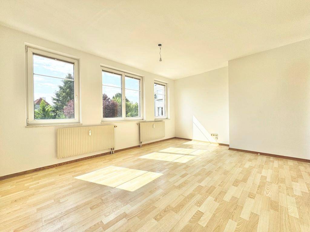 Lichtdurchfluteter Wohnbereich mit hellem Parkettboden und mehreren Fenstern für viel Tageslicht.