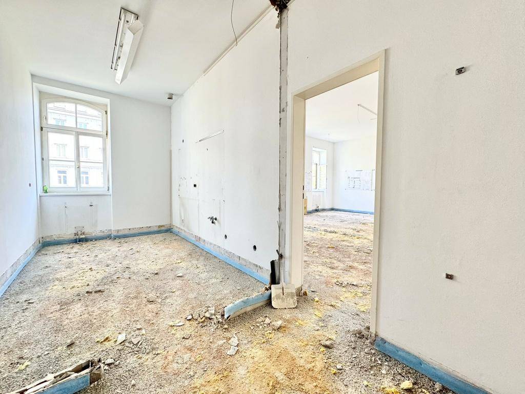 Leerer Raum in Renovierung mit Türöffnung zu einem weiteren Bereich und Tageslicht.