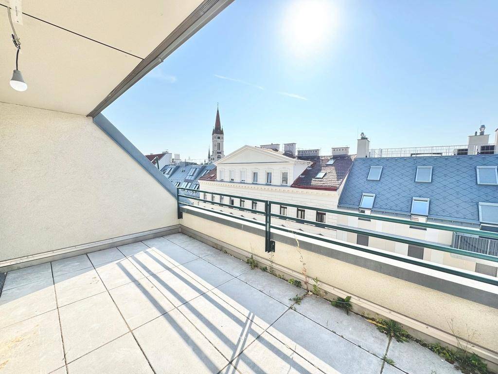 Helle Dachterrasse mit Fliesenboden und weitem Blick über die Stadt bis zur Kirchturmspitze.