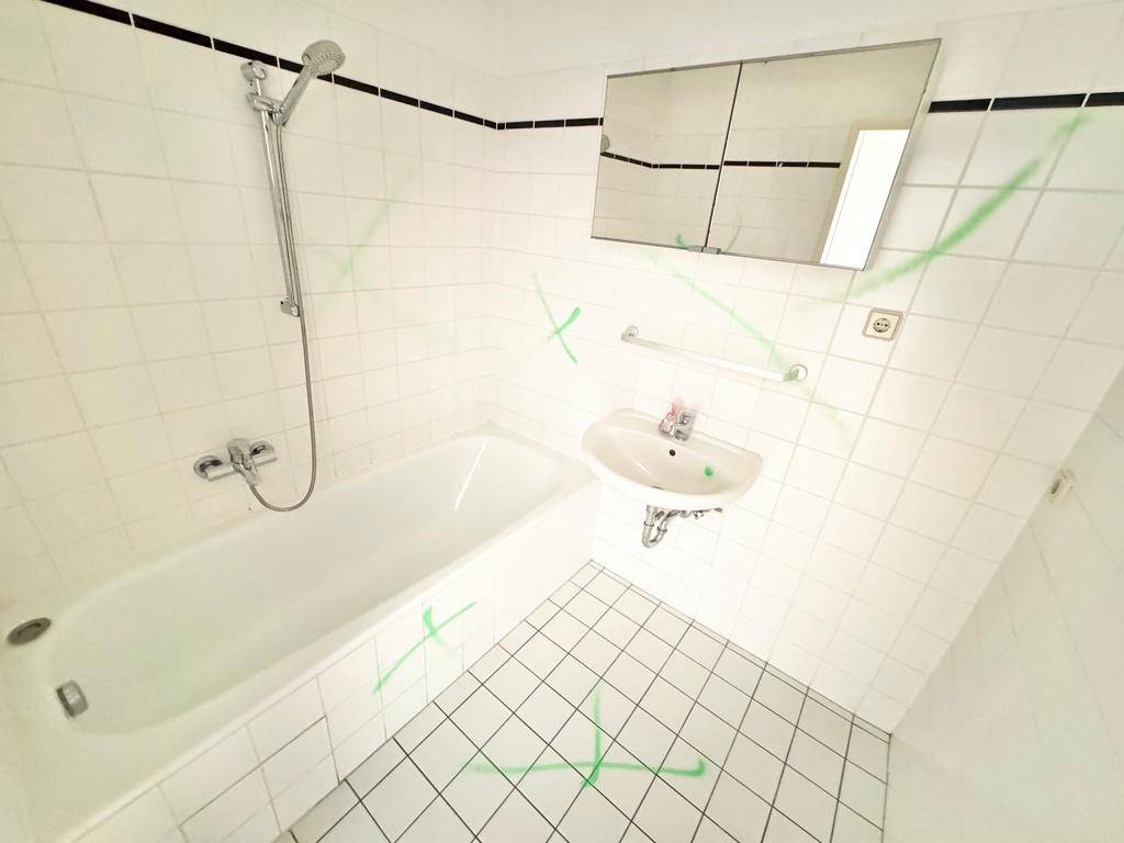 Gefliestes Badezimmer mit Badewanne, Duschfunktion, Einzelwaschbecken und Spiegelschrank.