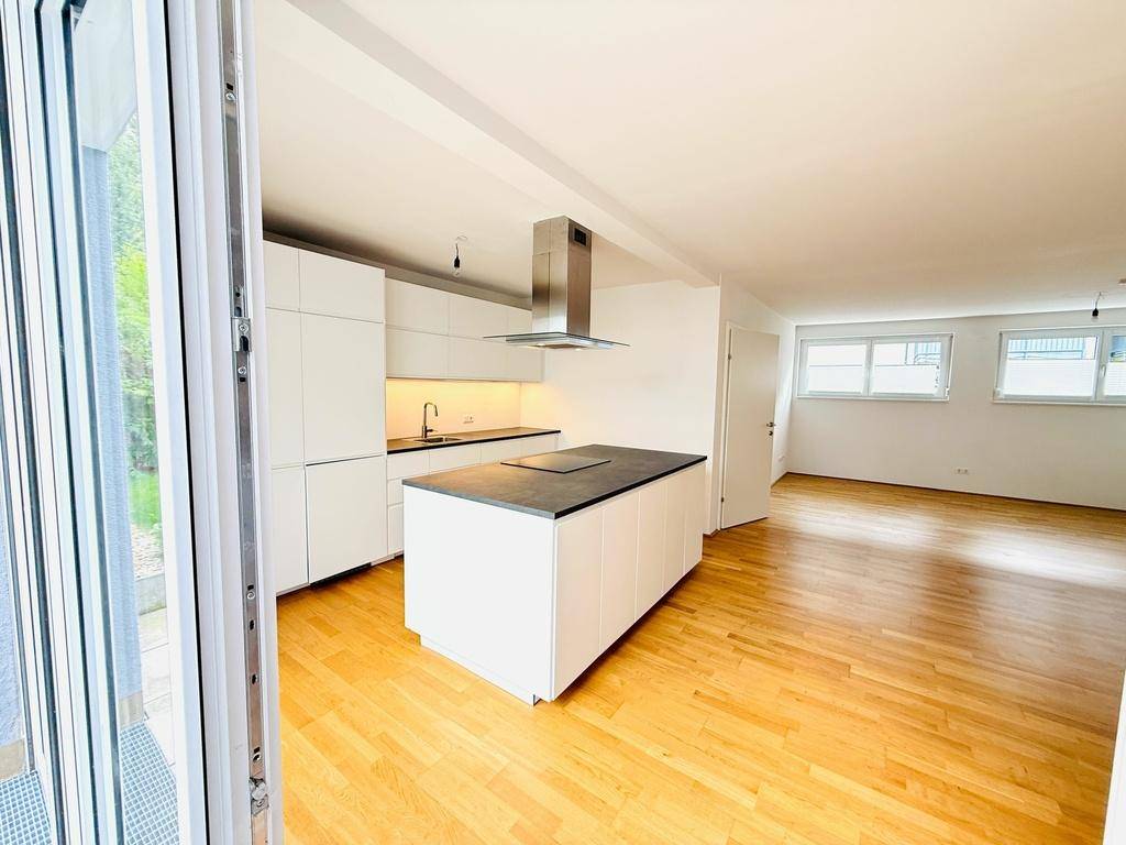 Moderne weiße Einbauküche mit Kücheninsel, Induktionskochfeld und direktem Terrassenzugang.