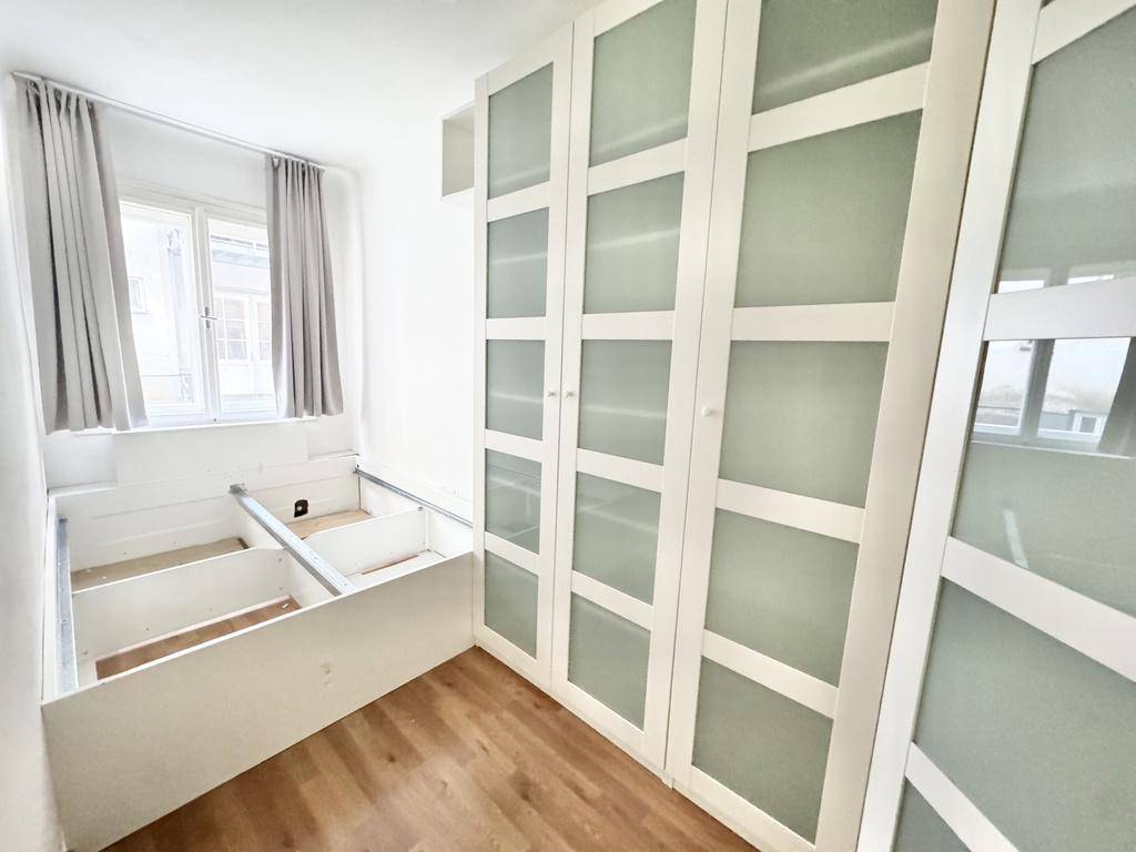 Kleines Schlafzimmer mit integriertem Bettrahmen, Stauraum und weißen Kleiderschränken.