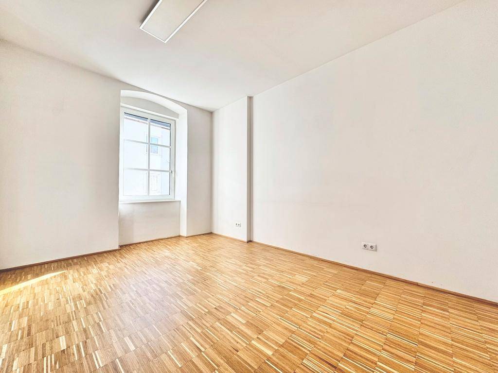 Geräumiges Zimmer mit Parkettboden und weiß gestrichenen Wänden, ideal als Schlaf- oder Arbeitszimmer.