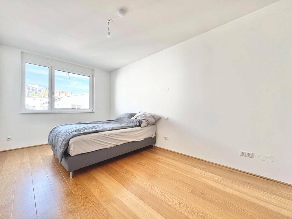 Ruhiges Schlafzimmer mit Holzboden und einem Fenster, das viel Tageslicht hereinlässt.