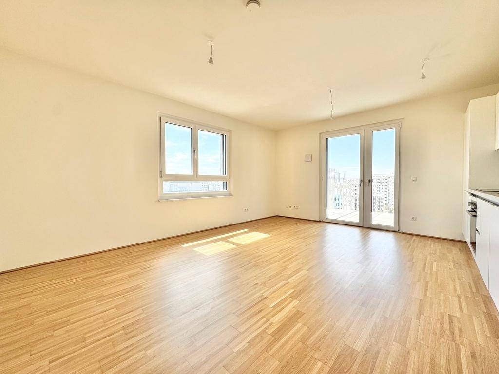 Lichtdurchfluteter Wohnbereich mit Zugang zum Balkon und weitem Blick auf die Stadtlandschaft.