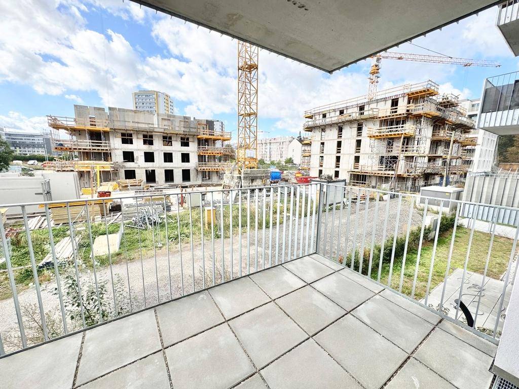 Balkon mit Fliesenboden und direktem Blick auf eine große Baustelle mit Kränen und Neubauten.