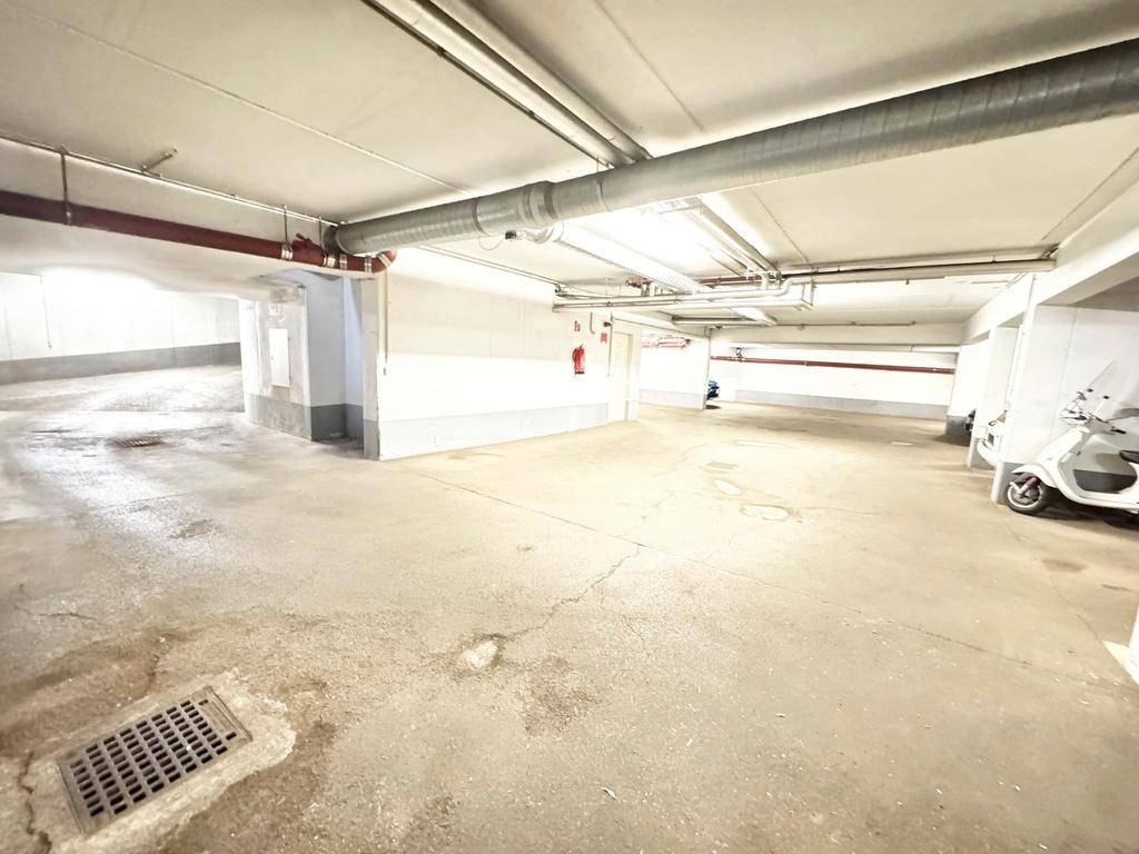 Weitläufige Tiefgarage mit mehreren Stellplätzen und Entwässerungsrinne im Vordergrund, sauber und ordentlich.