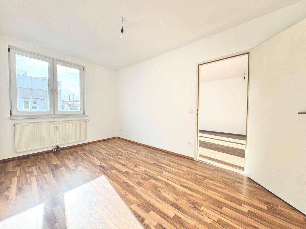 Helles, unmöbliertes Zimmer mit Laminatboden und einem Fenster, ideal als Schlaf- oder Arbeitszimmer.