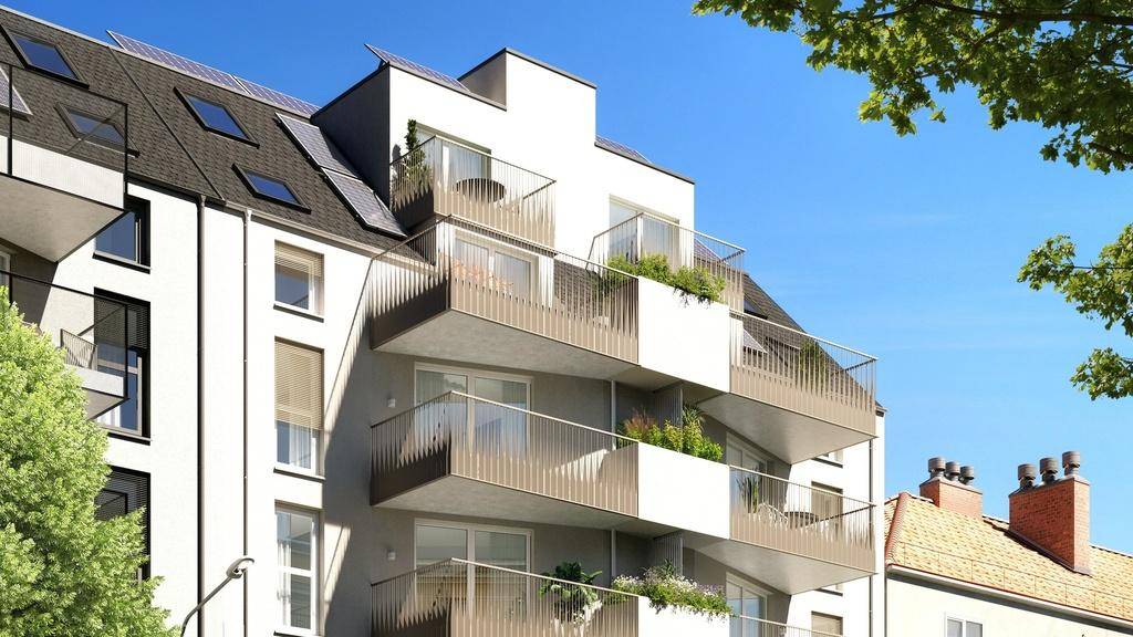Modernes Wohngebäude mit mehreren Balkonen, großen Fenstern und Photovoltaikanlage auf dem Dach.