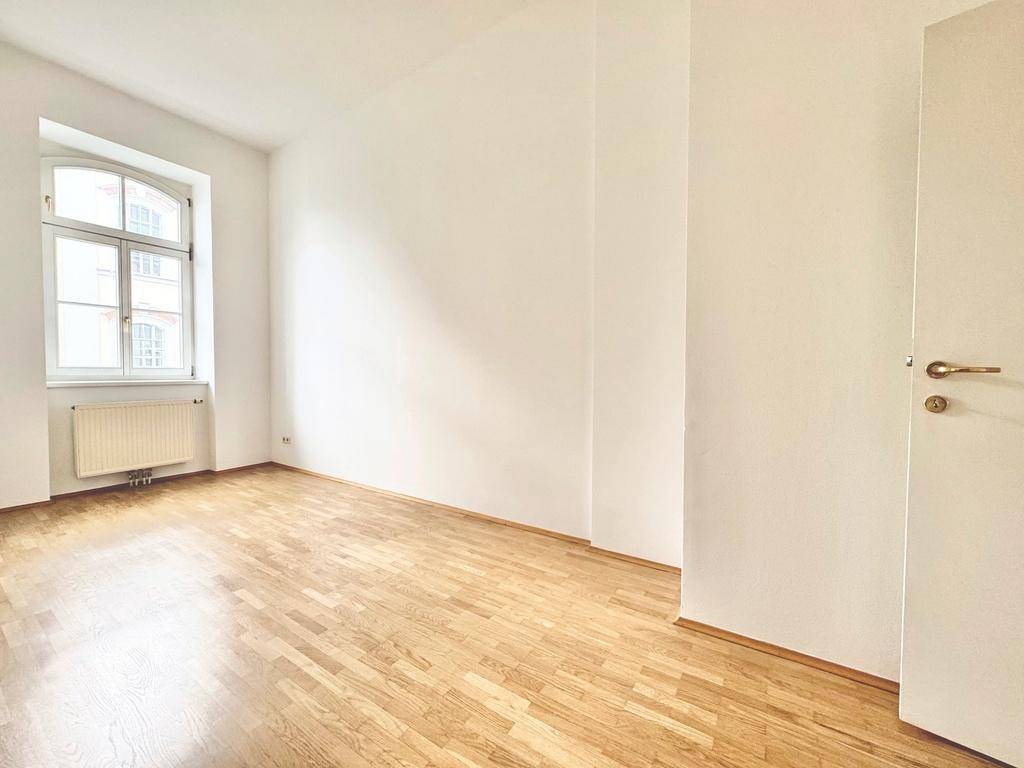 Geräumiges Schlafzimmer mit Parkettboden und einem Fenster, das eine ruhige Atmosphäre bietet.