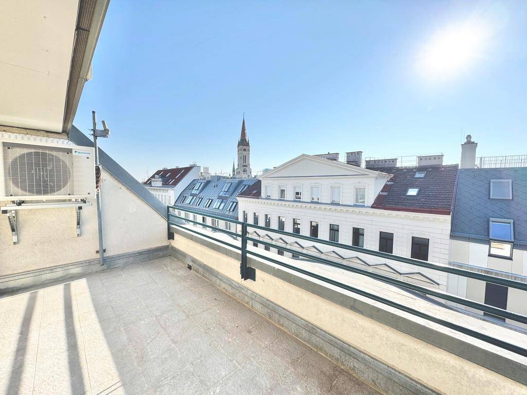 Helle Dachterrasse mit Panoramablick über die Stadt und historische Gebäude, inklusive Klimaanlage.