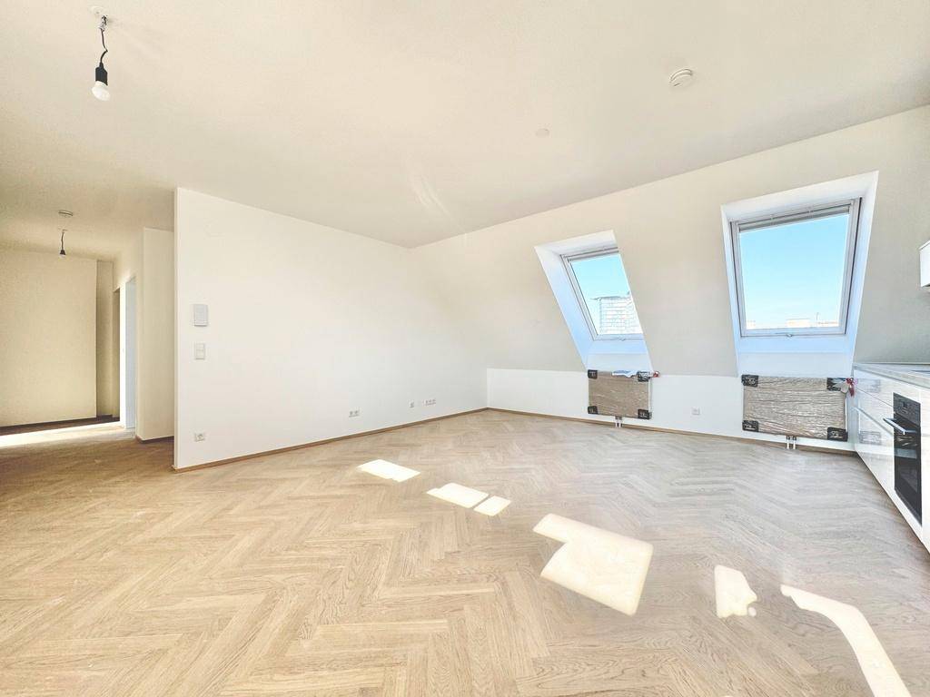 Heller Wohnbereich im Dachgeschoss mit Fischgrätparkett und Dachfenstern, die viel Tageslicht hereinlassen.