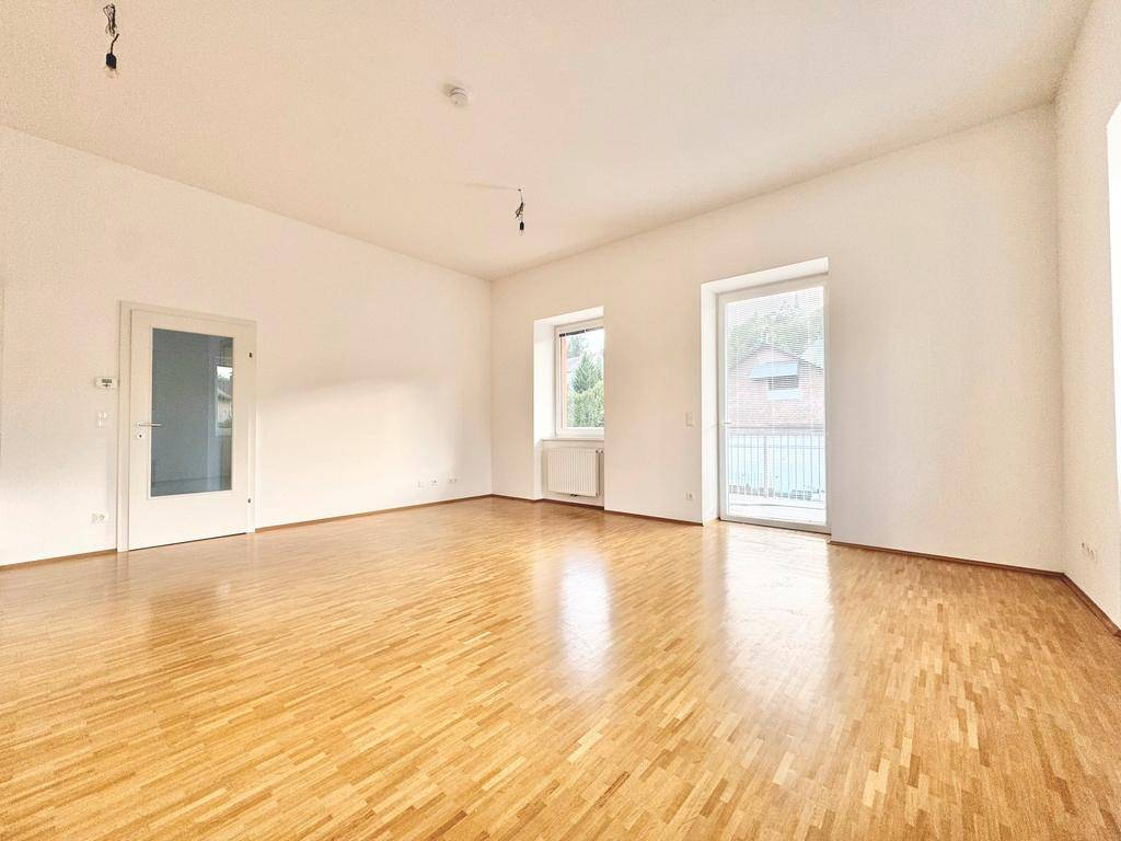Heller Wohnraum mit Parkettboden und Zugang zu einem Balkon, ideal für individuelle Gestaltung.