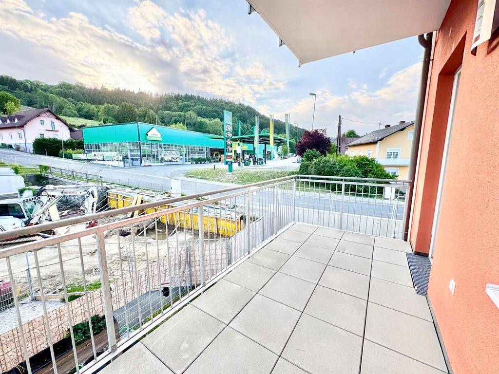 Heller Balkon mit Fliesenboden und weitem Blick über die Nachbarschaft und grüne Landschaft.