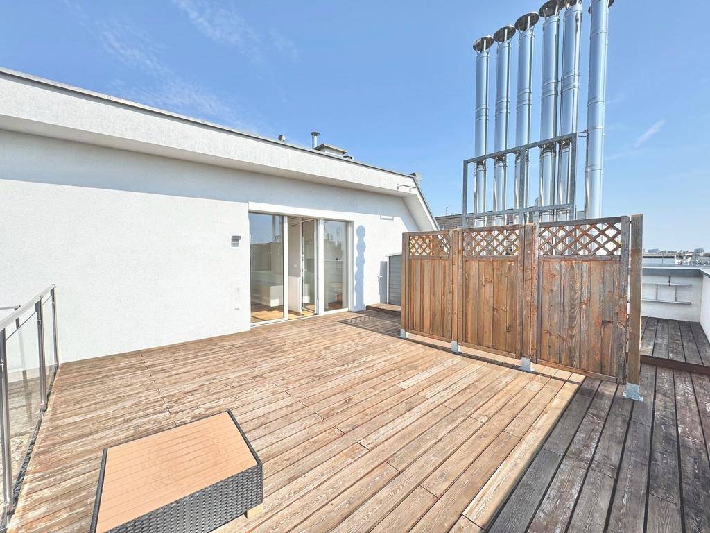 Weitläufige Dachterrasse mit Holzboden und Schiebetüren, die einen direkten Zugang zum Innenbereich ermöglichen.