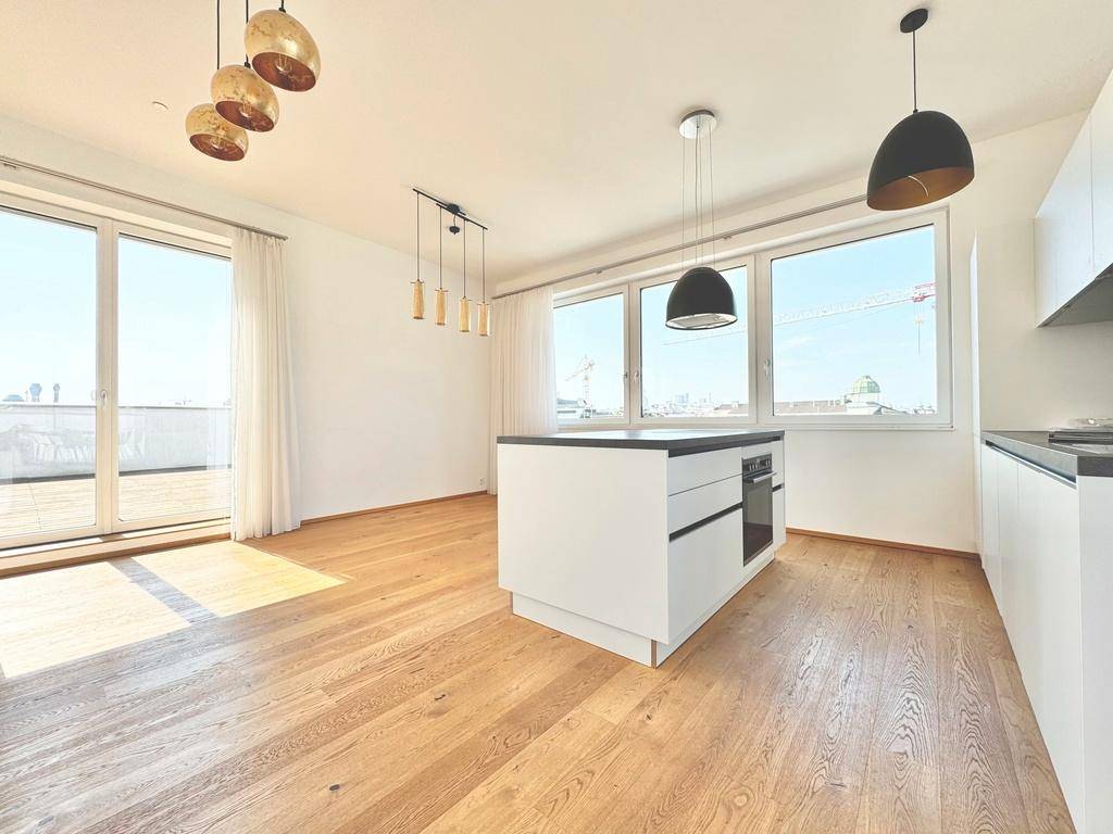 Geräumiger Wohnbereich mit moderner Kücheninsel, Holzboden und direktem Zugang zur sonnigen Terrasse.