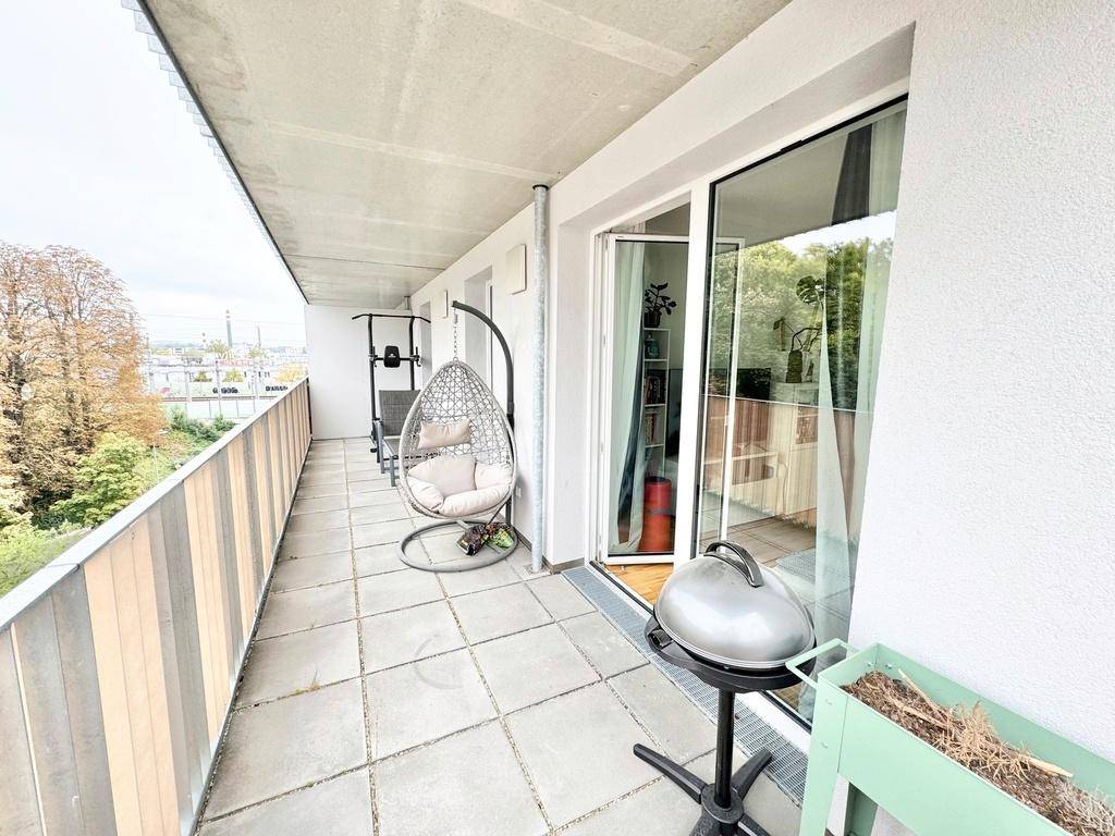 Heller Balkon mit Grill und Hängesessel, perfekt für entspannte Stunden im Freien.