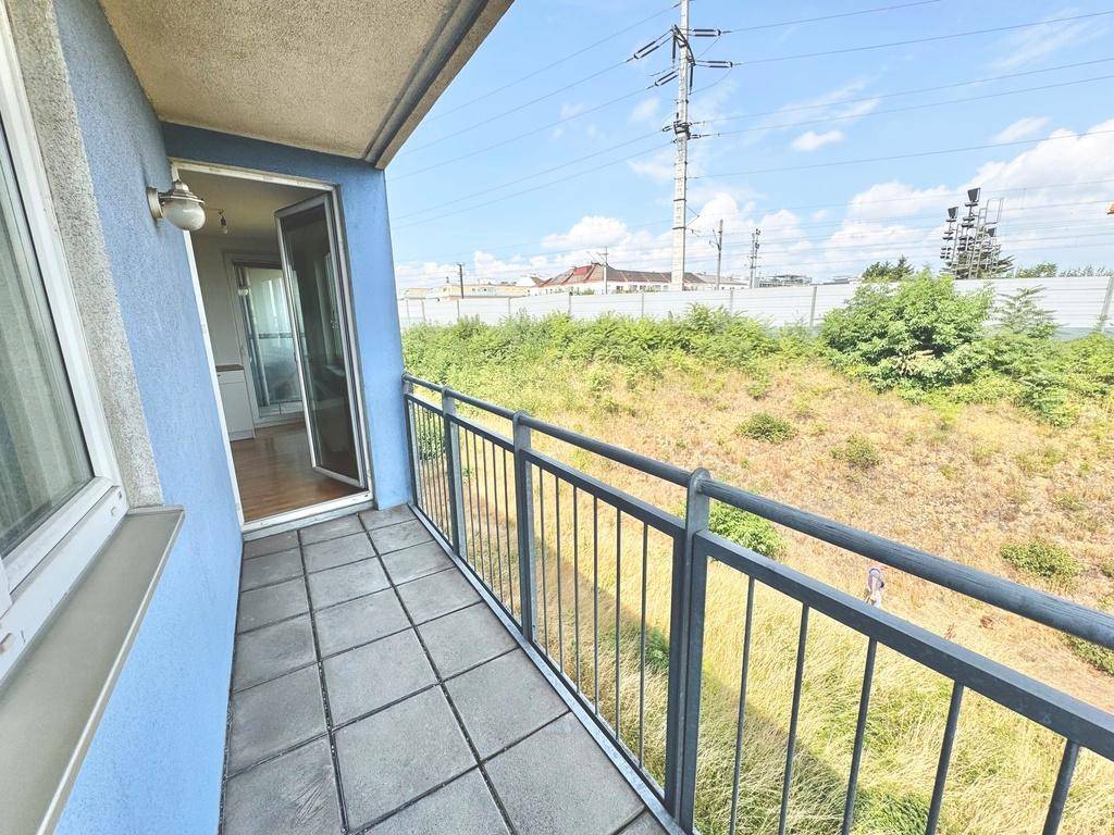 Balkon mit Zugang zum Innenbereich und Blick auf die Umgebung mit Strommasten.