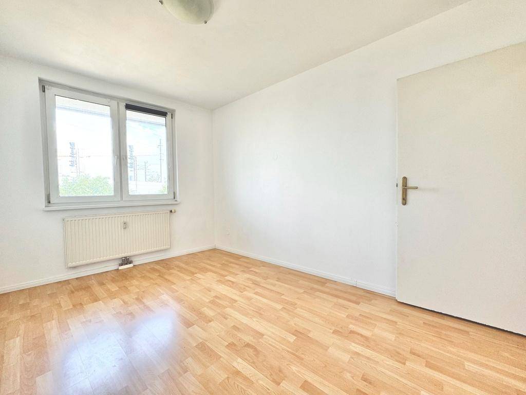 Ruhiges Zimmer mit Parkettboden und Fenster, geeignet als Schlaf- oder Kinderzimmer.