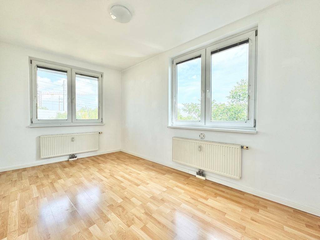 Helles Zimmer mit Parkettboden und zwei großen Fenstern, ideal als Schlaf- oder Arbeitszimmer.