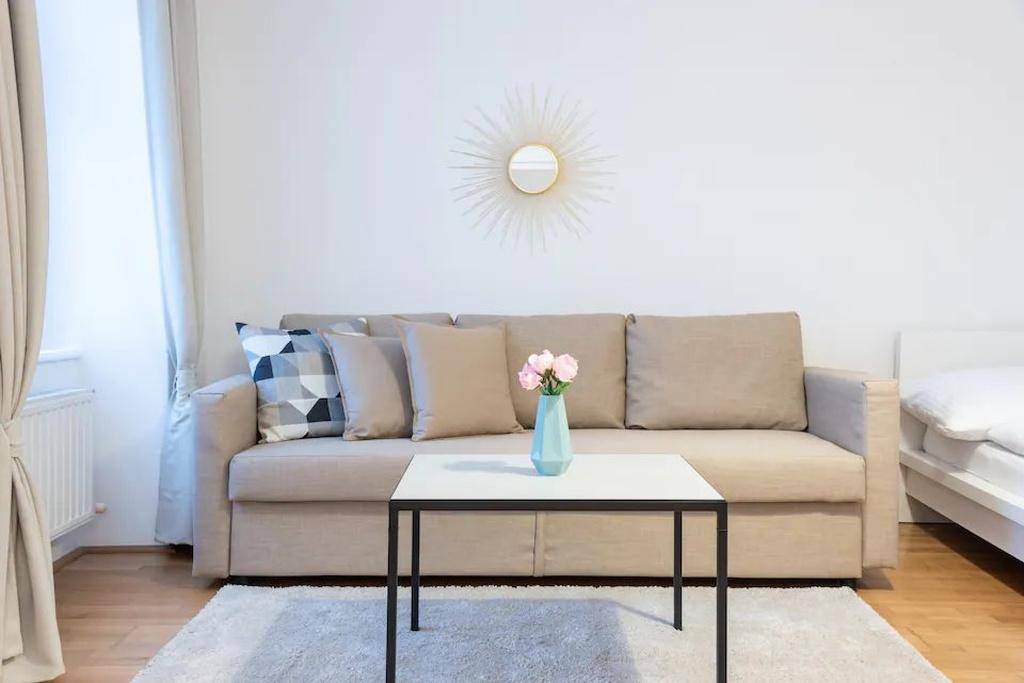 Gemütlicher Wohnbereich mit beigem Sofa, Couchtisch und einem dekorativen Wandspiegel.