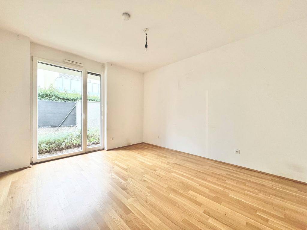 Lichtdurchflutetes Zimmer mit Holzboden und bodentiefen Fenstern zum Garten.