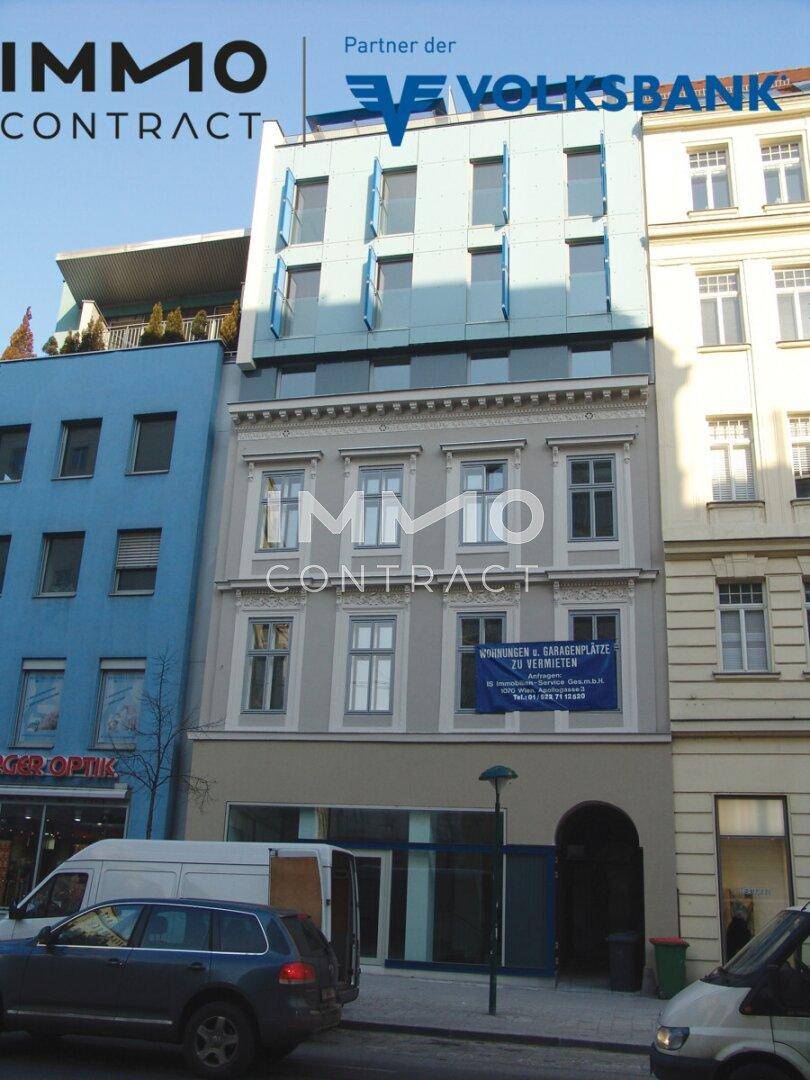 Die Vorderansicht des Gebäudes mit einer Mischung aus klassischer und moderner Architektur und einem 'Zu Vermieten'-Schild.