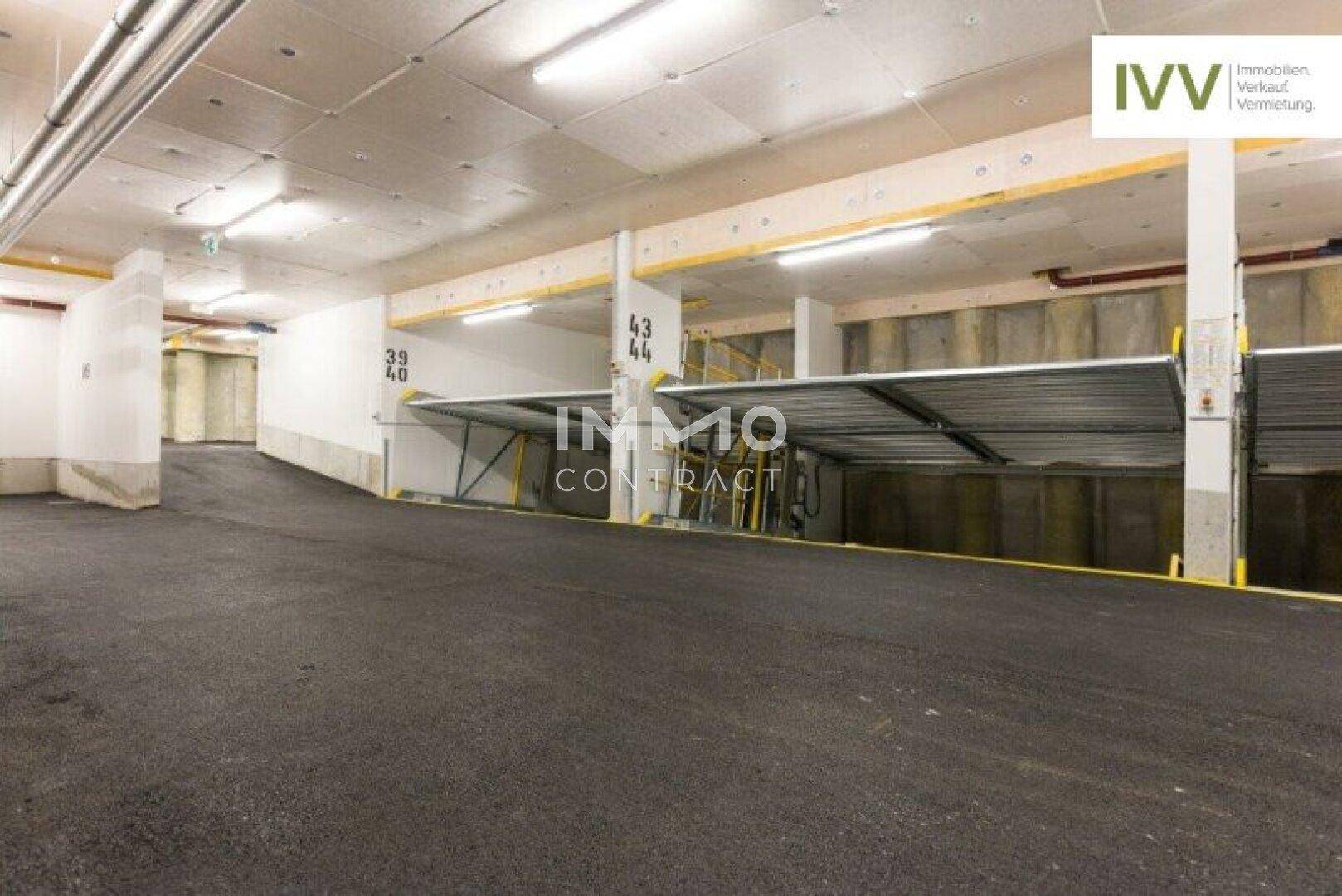 Geräumige Tiefgarage mit modernen Doppelparkern und Zufahrtsrampe für Fahrzeuge.