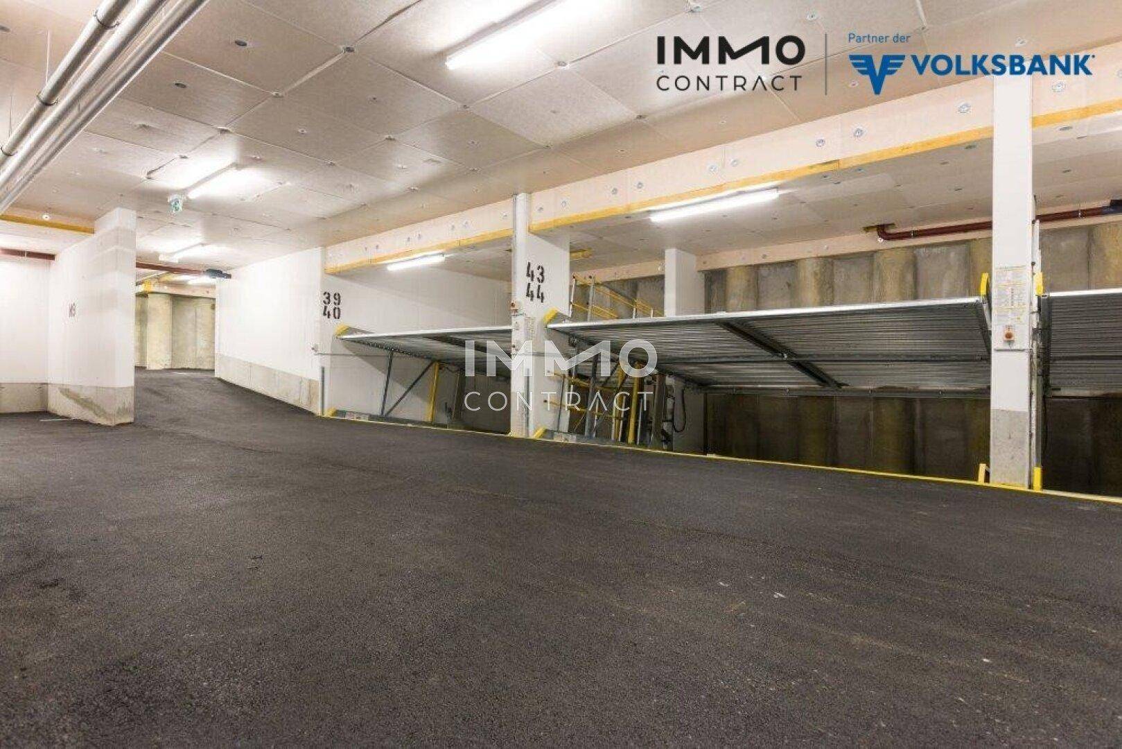 Geräumige Tiefgarage mit modernen Parkliftsystemen und einer Zufahrtsrampe für Fahrzeuge.