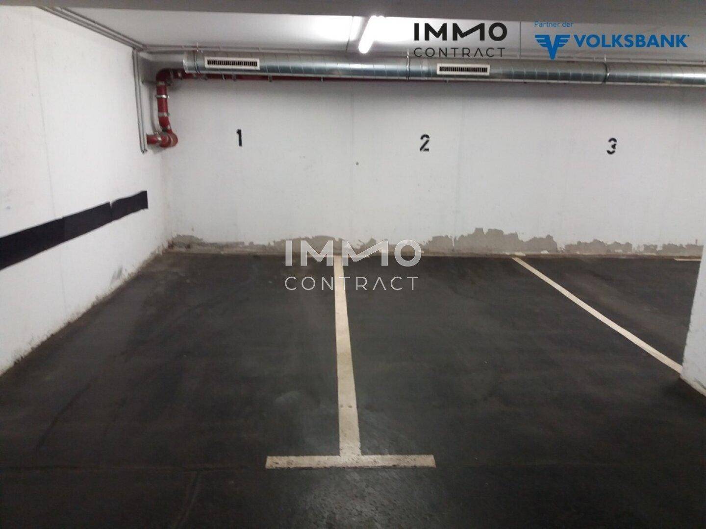 Leerer Parkplatz in einer Tiefgarage mit nummerierten Stellflächen und Betonwänden.
