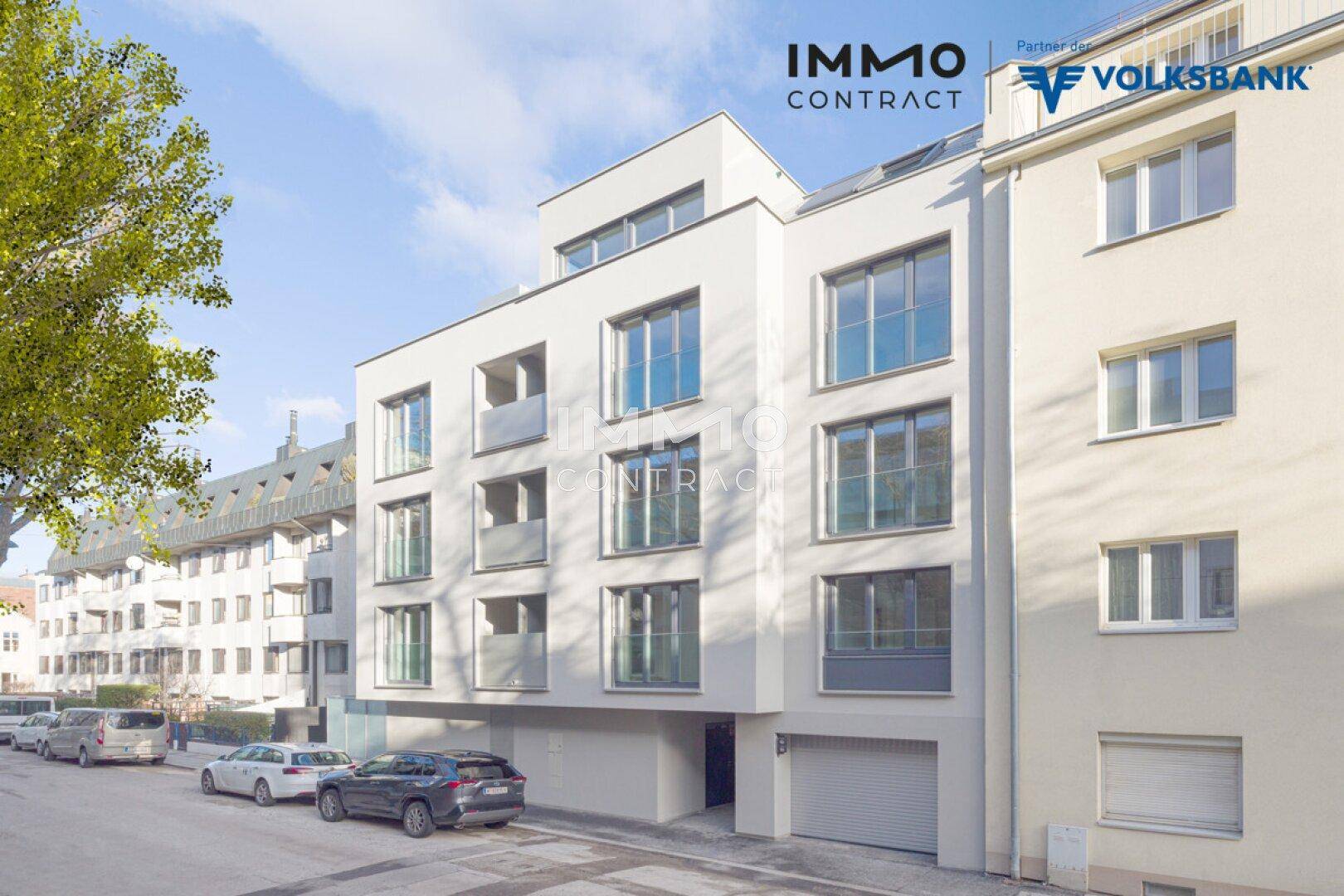 Moderne Wohnanlage mit heller Fassade, großen Fenstern und Balkonen an einer Stadtstraße.