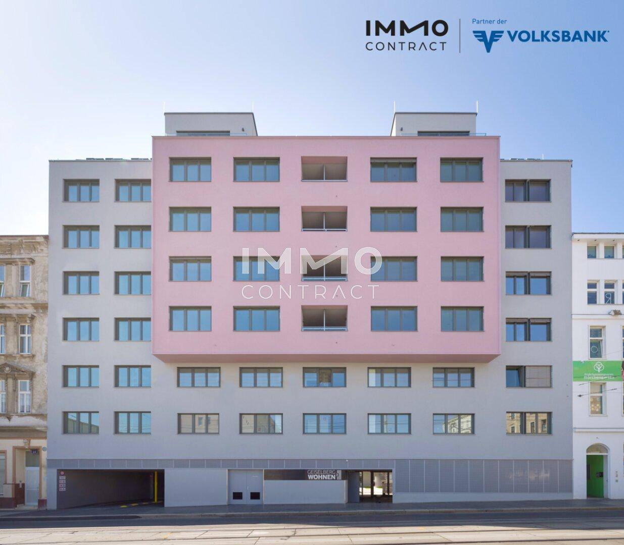 Modernes Mehrfamilienhaus mit markanter rosa Fassade und vielen Fenstern in urbaner Umgebung.