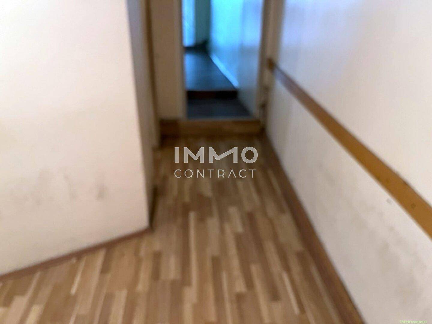 Langer, schmaler Flur mit Laminatboden, der verschiedene Bereiche des Gebäudes verbindet und eine funktionale, aber einfache Ausstattung zeigt.