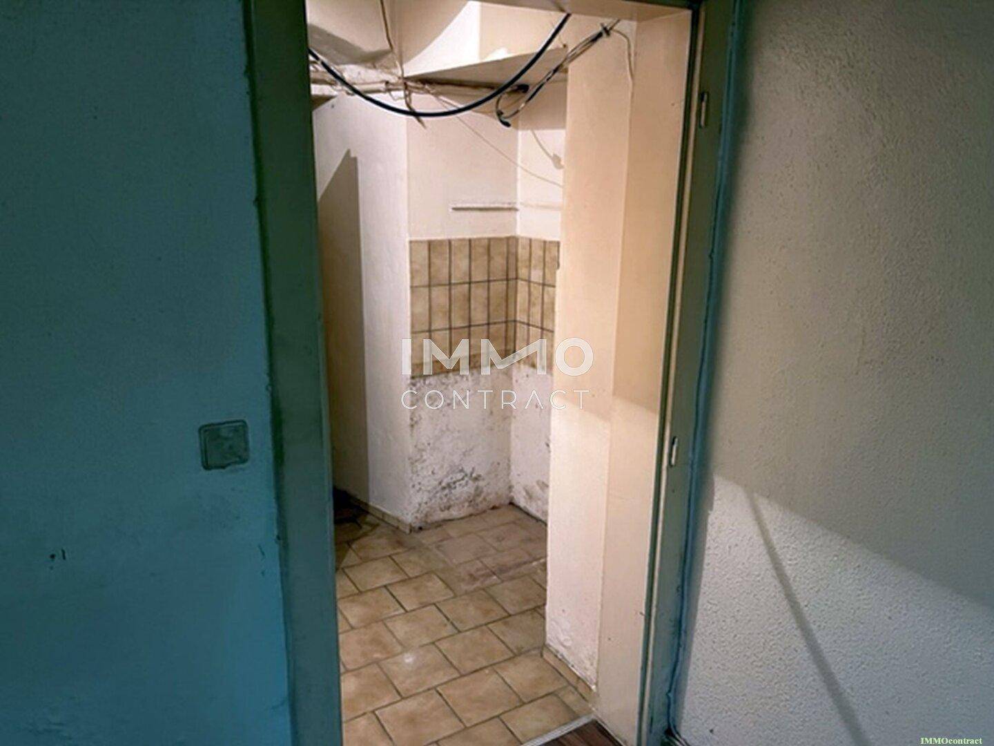 Kleiner Abstellraum mit Fliesenboden und teilweise gefliesten Wänden, der sich in einem renovierungsbedürftigen Zustand befindet.