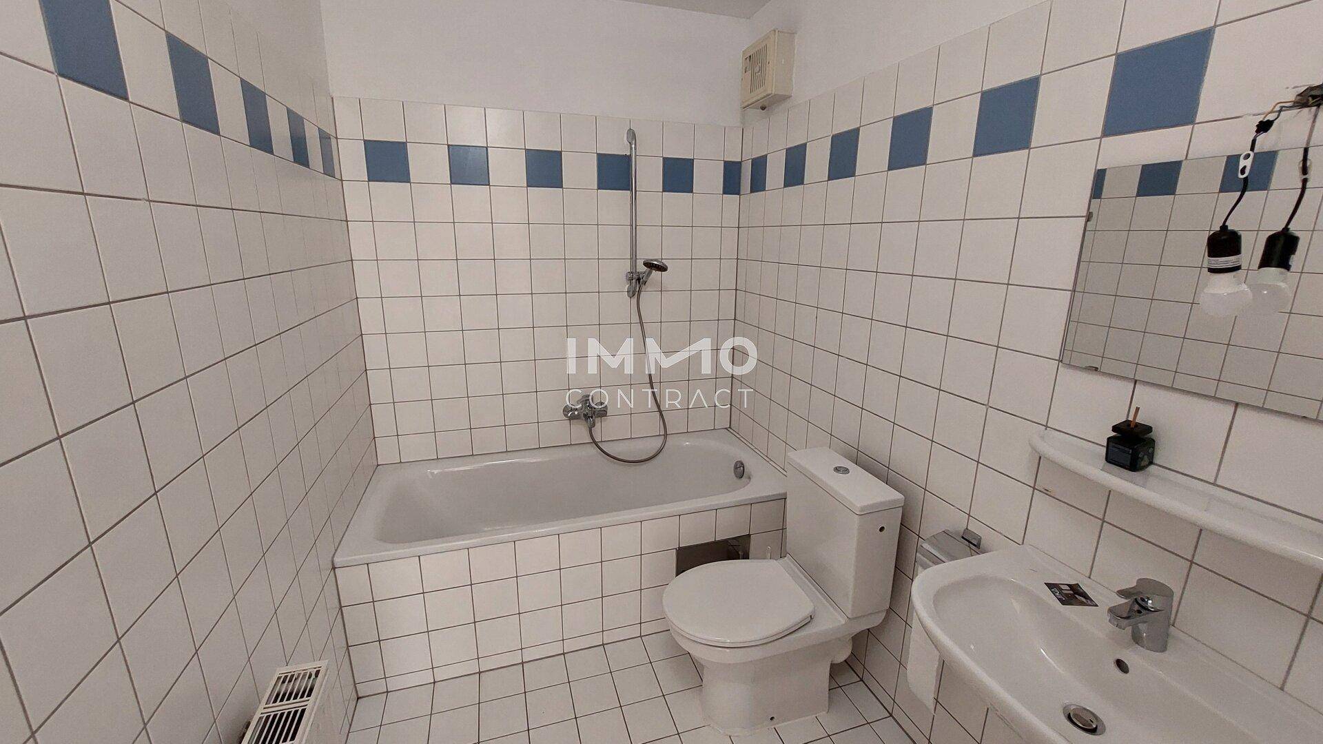 Gefliestes Badezimmer mit Badewanne, Toilette und Waschbecken in einem klassischen weiß-blauen Design.