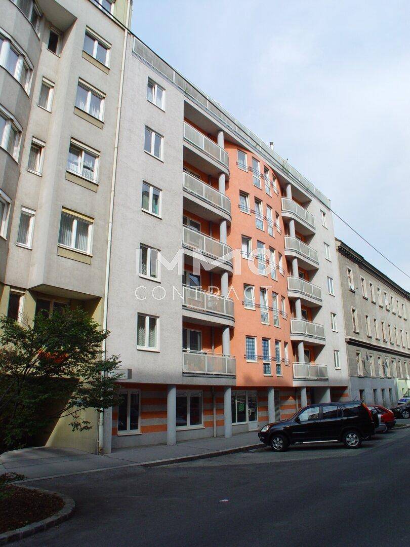 Moderne Wohnhausfassade mit orangefarbenen Akzenten, vielen Balkonen und großen Fenstern.